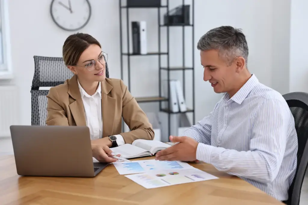 A woman and a man sitting at a desk in an office, reviewing charts and graphs with an Orlando FL bookkeeper.