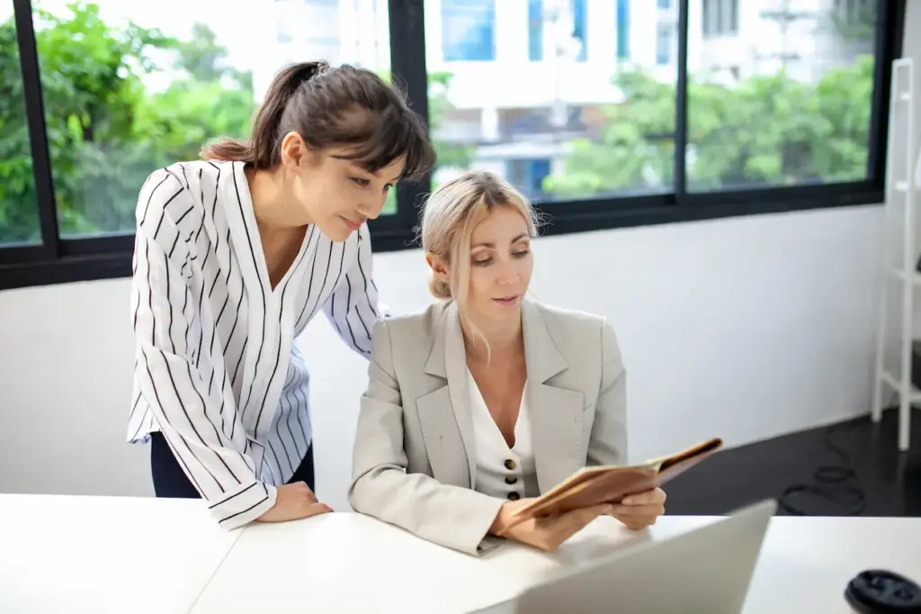 Two women in an Orlando, FL office looking at an open bookkeeper notebook together.