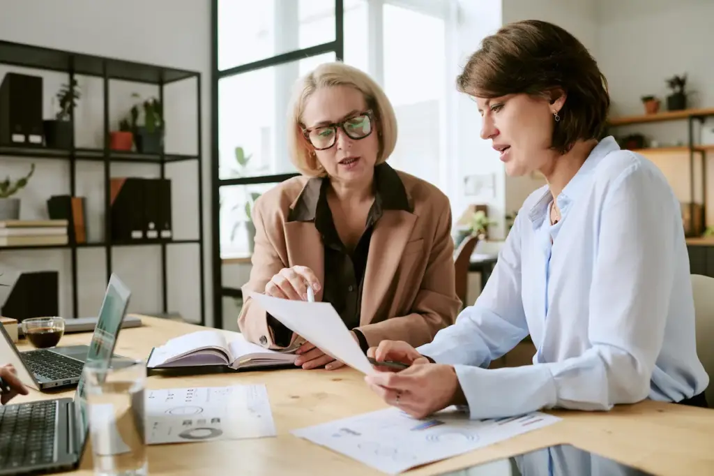 Two businesswomen reviewing a document together at an office desk for bookkeeping services in Kissimmee.